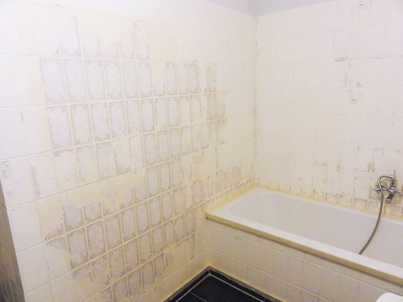 badezimmer abgenutzte weisse fliesen fliesenreste einbaubadewanne dunkle bodenfliesen