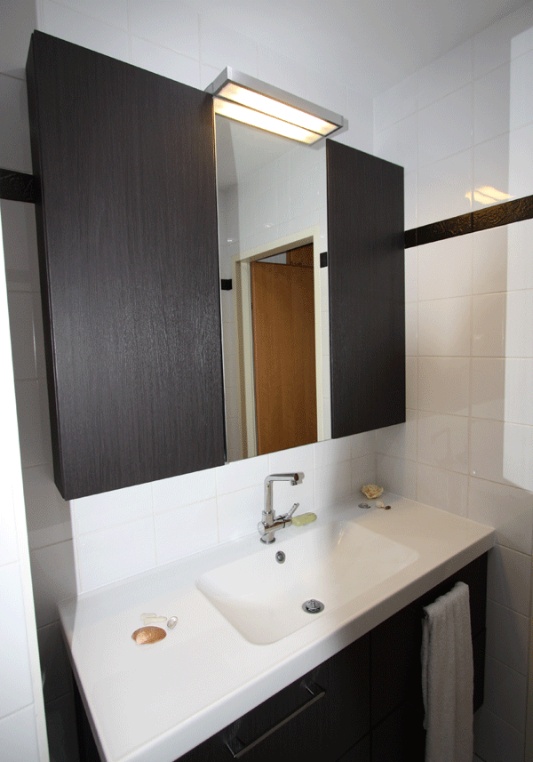 badezimmer spiegelschrank dunkles holzdekor einbauwaschtisch weisse fliesen schwarze bordure