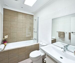Ratgeber : Badsanierung Munchen Badezimmer Holzoptik Fliesen Einbaubadewanne Duschwand Weisse Wandfliesen Grosser Spiegel Badsanierung München: Kosten, Planung Und Besonderheiten