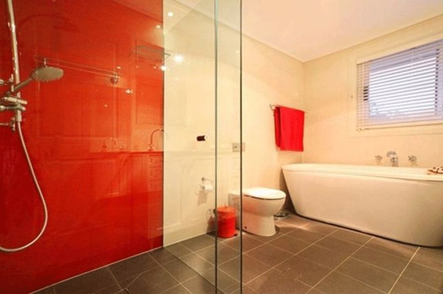 badezimmer rote glaswand dusche freistehende badewanne graue bodenfliesen