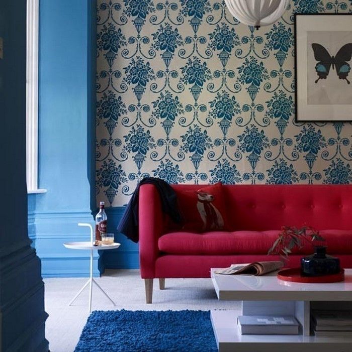 wohnzimmer mit blauer ornamenttapete und rotem sofa