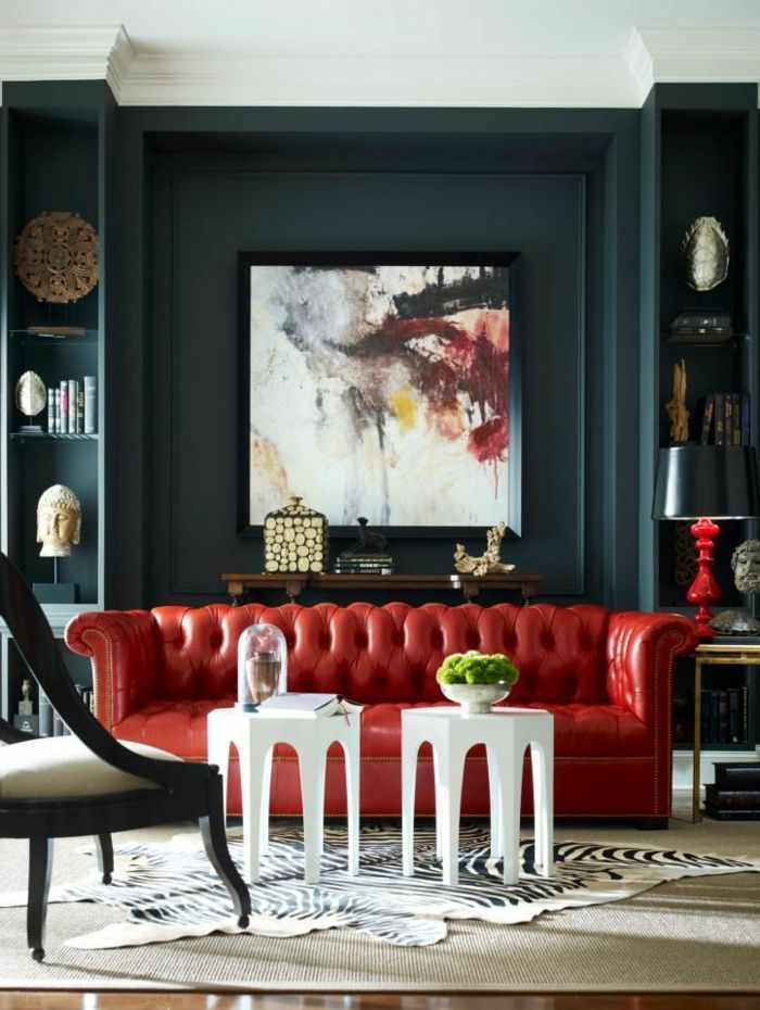 wohnzimmer mit rotem chesterfield sofa und dunkler wand