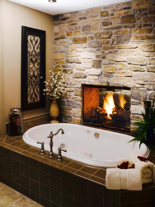 badewanne mit steinwand und durchsichtigem kamin
