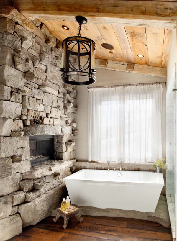 rustikales badezimmer mit natursteinwand und freistehender badewanne